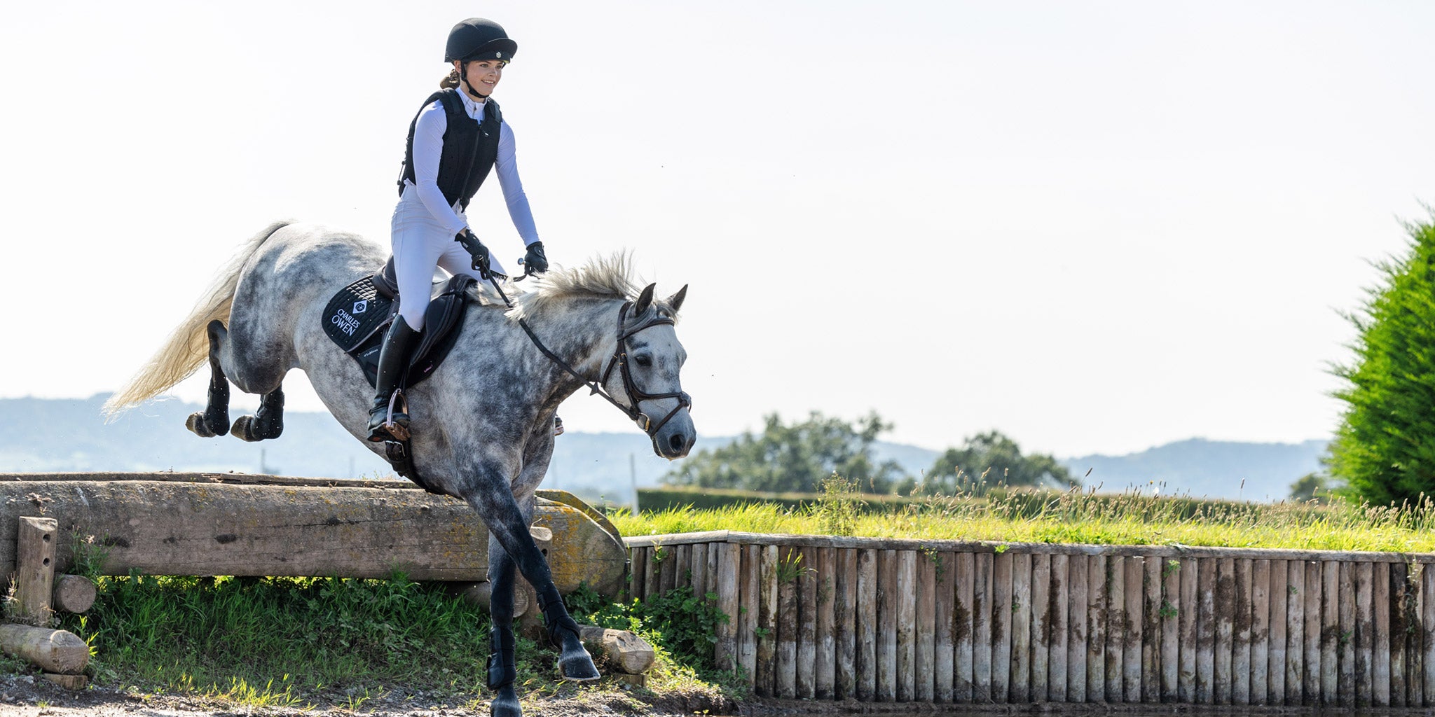 Person riding a horse over an obstacle in an outdoor equestrian setting